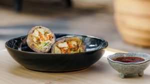 tofu sushi roll in bowl with sauce